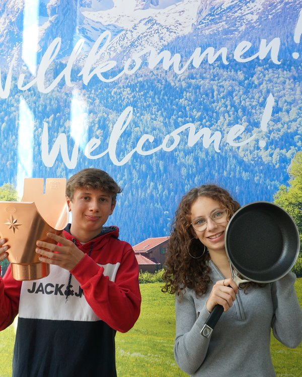 Ein Junge der einen Einhangstutzen hochhält und ein Mädchen das eine Pfanne hochhält | © RÖSLE GROUP Ein Junge der einen Einhangstutzen hochhält und ein Mädchen das eine Pfanne hochhält | © RÖSLE GROUP