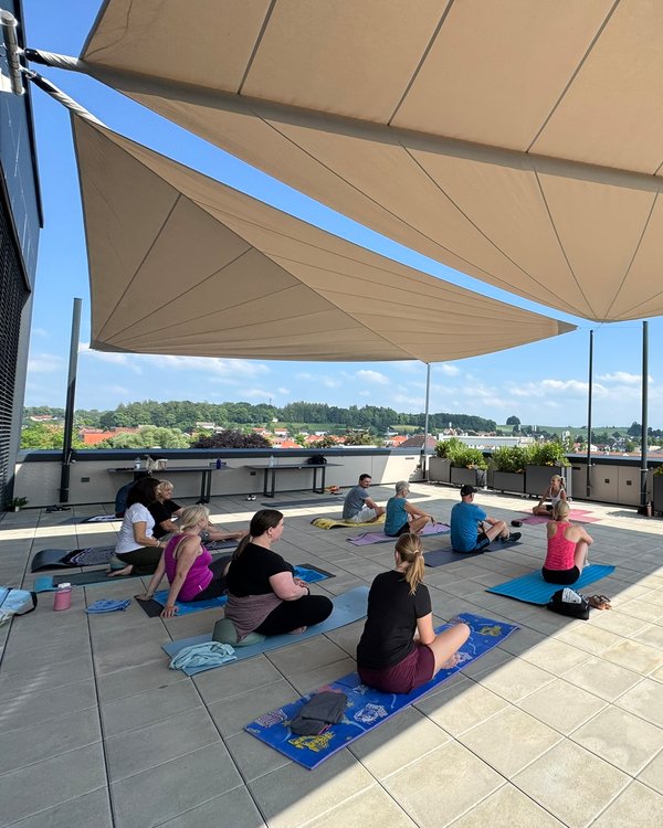 Afterwork Yoga | © RÖSLE GROUP Eine Gruppe Menschen, die auf Yogamatten, auf der Dachterasse der RÖSLE Kochschule sitzen. | © RÖSLE GROUP