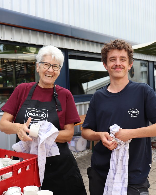 Grillfest 2025 | © RÖSLE GROUP ein Frau und ein Junge stehen neben einander und trocknen Geschirr auf einem Rösle Fest ab und lächeln in die Kamera | © RÖSLE GROUP