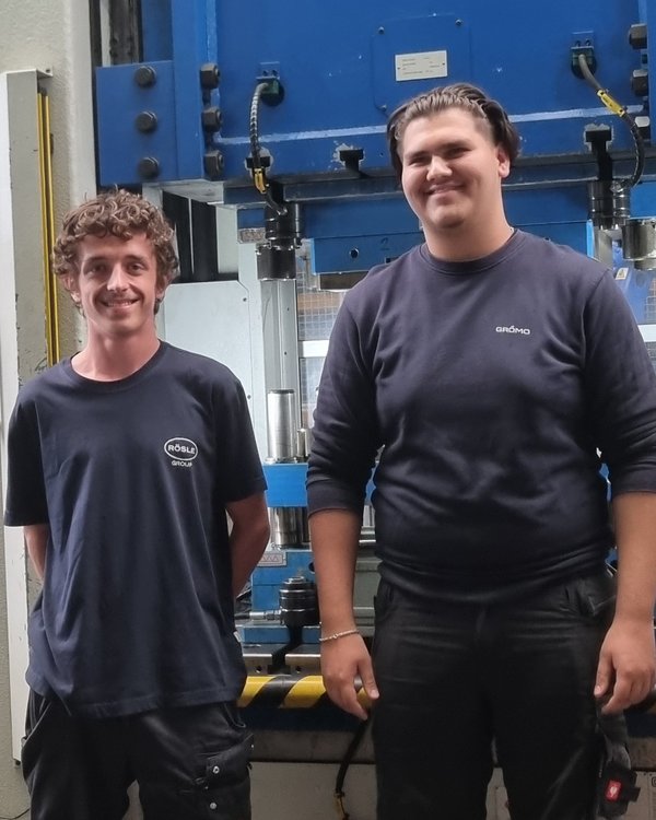 2 Jungen stehen vor einer Maschine. Sie werden fotografiert und lächeln in die Kamera | © RÖSLE GROUP